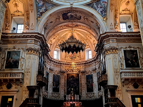 Prachtvoller Innenraum der Kathedrale von Bergamo mit barocker Kuppel, vergoldeten Stuckverzierungen, großformatigen Gemälden und schwarz-weiß gemustertem Marmorboden.